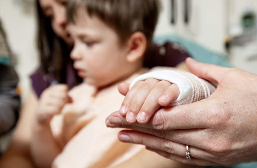 Female adult holding a child's bandaged hand.