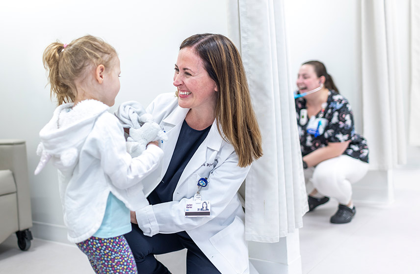 Cleveland Clinic doctor smiling and embracing a child.