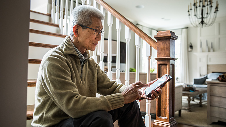 Man sitting on steps in his home looking at phone concerned