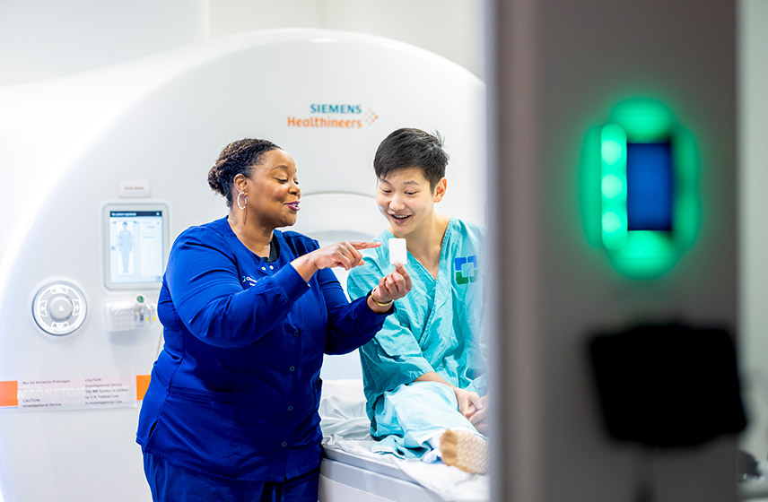 Cleveland Clinic caregiver with patient sitting on a bed before getting a scan.